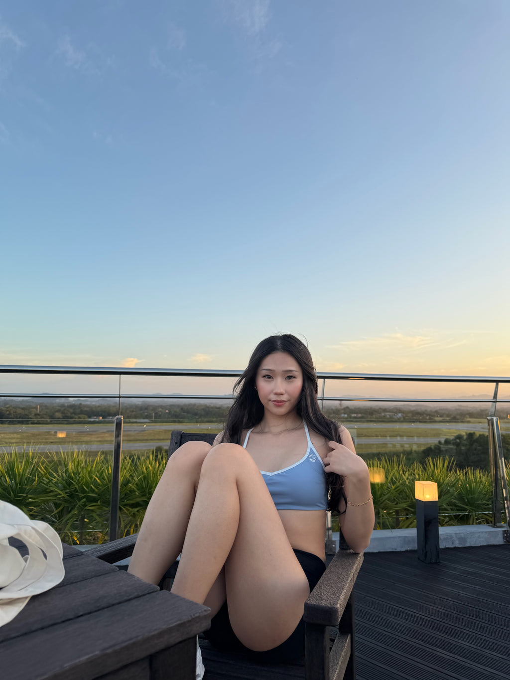 Woman sitting on a rooftop with a scenic view at sunset