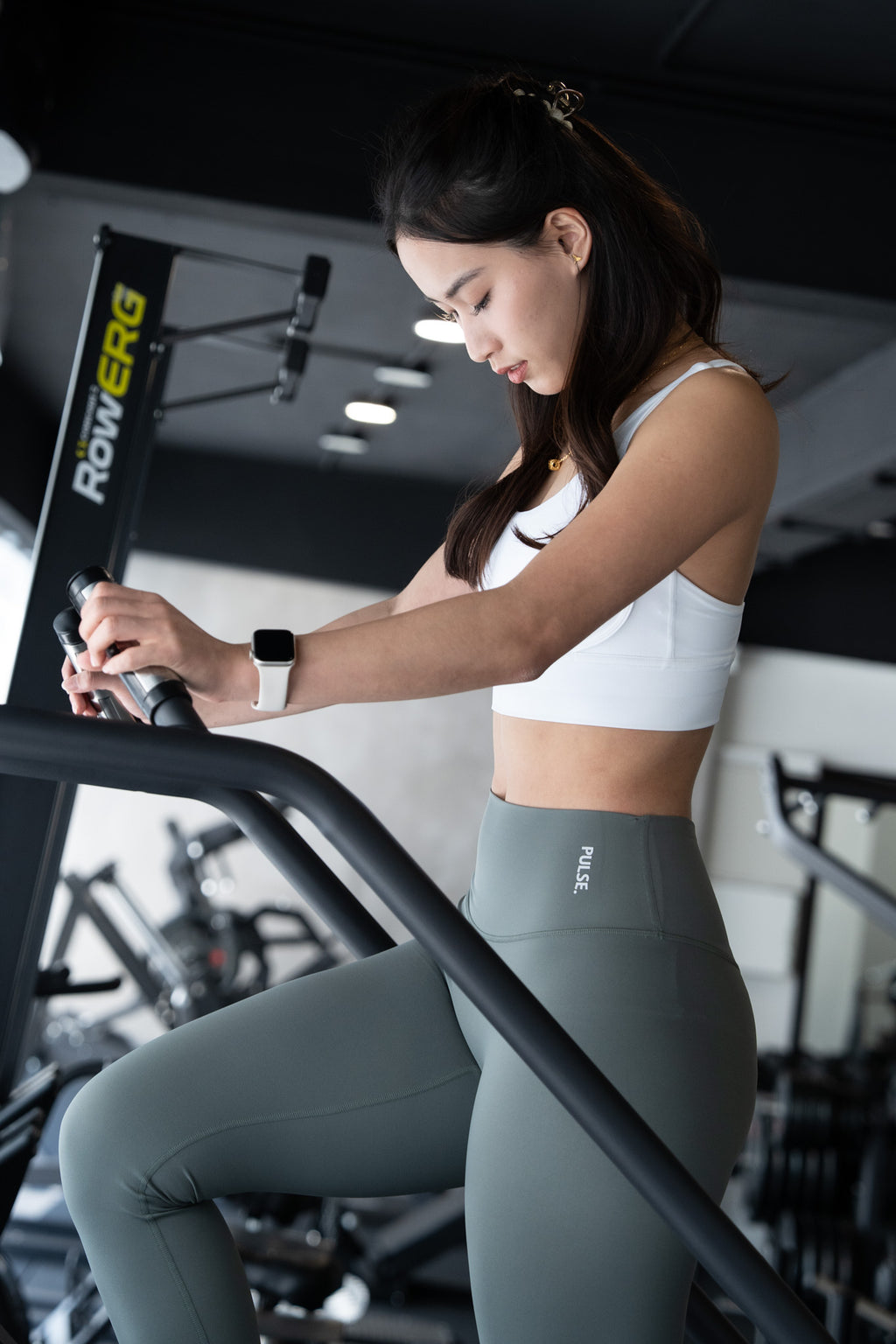 Woman exercising on a Rowing Erg machine in a gym setting