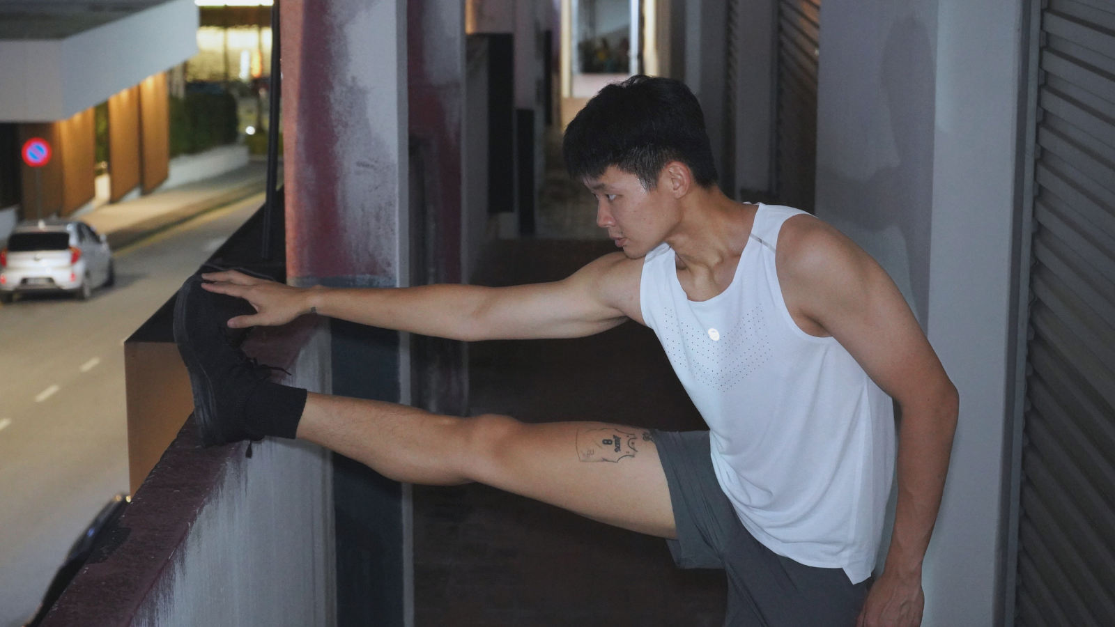 Person stretching against a wall at night